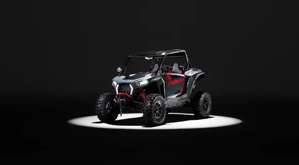 A 2026 Polaris RZR XP Ultimate SxS in the Stealth Gray colorway entrenched in light while parked in a dark garage.