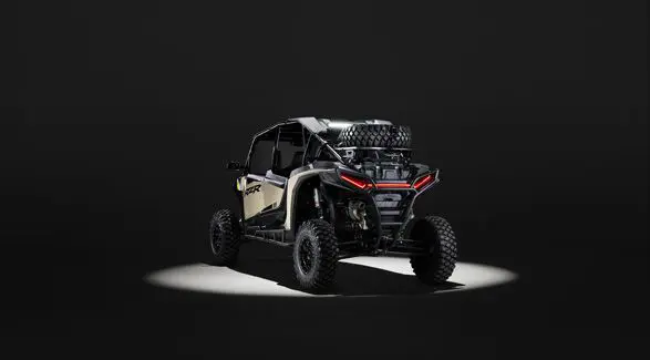 Rear view of a 2026 Polaris RZR XP 4 Ultimate SxS in the Sand Dune colorway entrenched in light while parked in a dark garage.