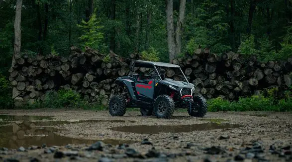 A 2026 Polaris RZR XP Ultimate SxS in the Stealth Gray colorway parked near a logged out forest.