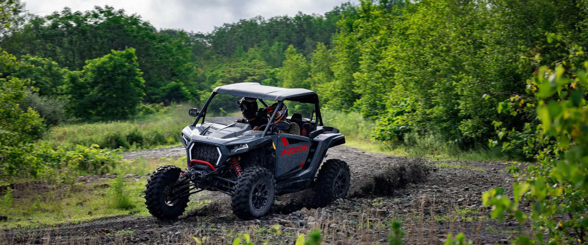 2 riders in a 2026 Polaris RZR XP Ultimate SxS in the Stealth Gray colorway taking a tight corner with ease.