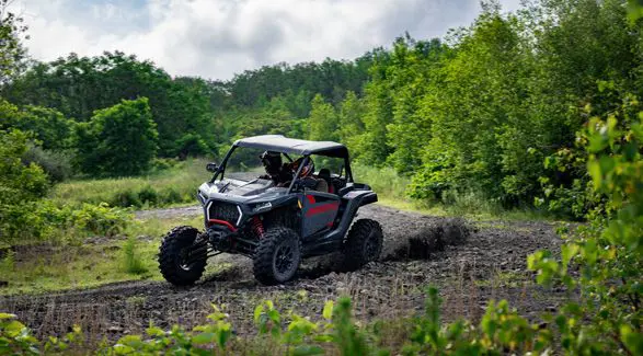 2 riders in a 2026 Polaris RZR XP Ultimate SxS in the Stealth Gray colorway taking a tight corner with ease.