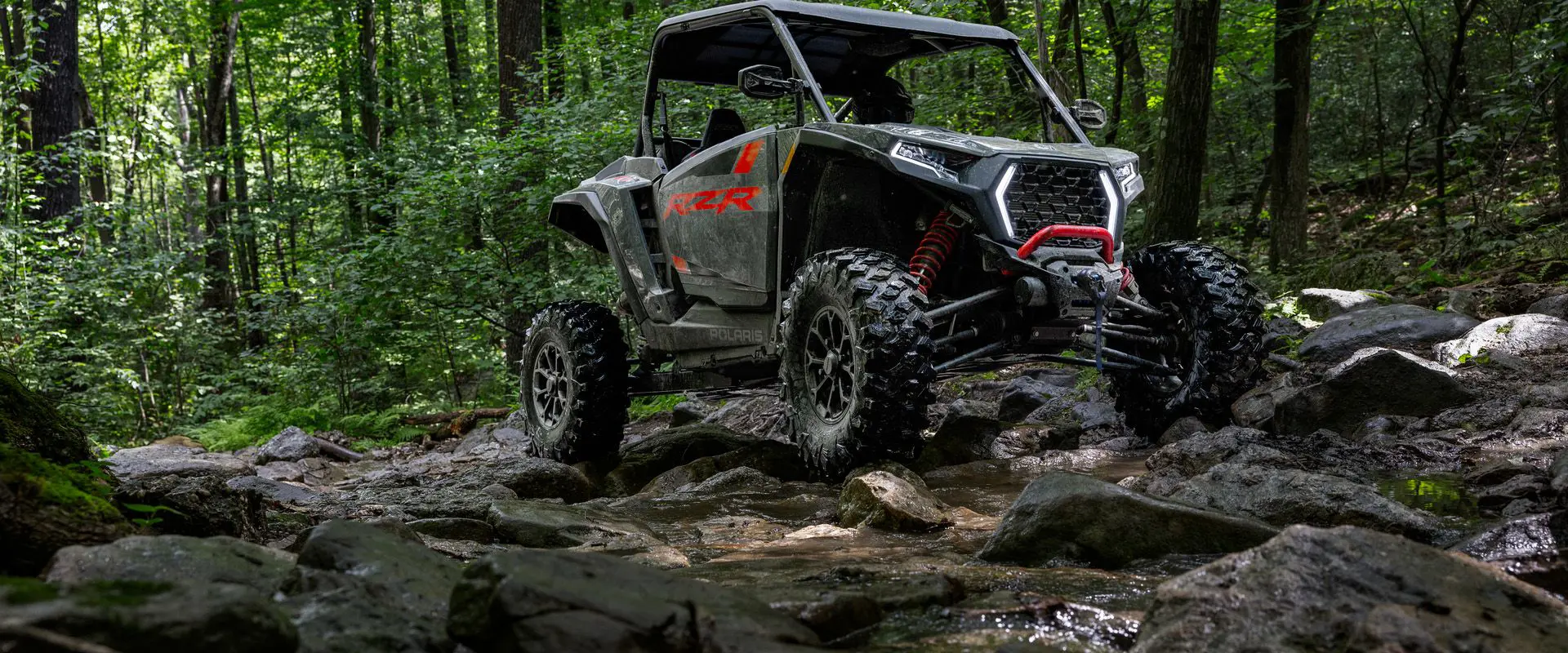 A 2026 Polaris RZR XP Ultimate SxS in the Stealth Gray colorway crawling over rocky uneven terrain like a champ.