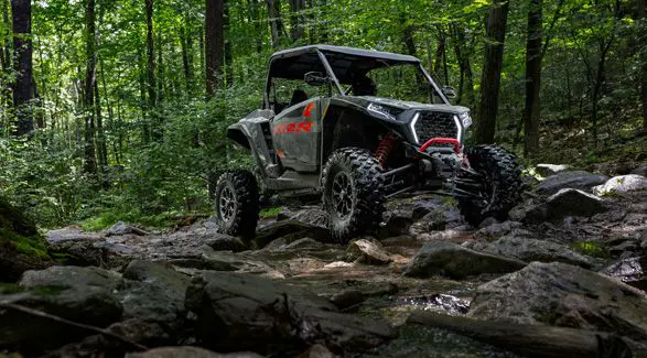 A 2026 Polaris RZR XP Ultimate SxS in the Stealth Gray colorway crawling over rocky uneven terrain like a champ.