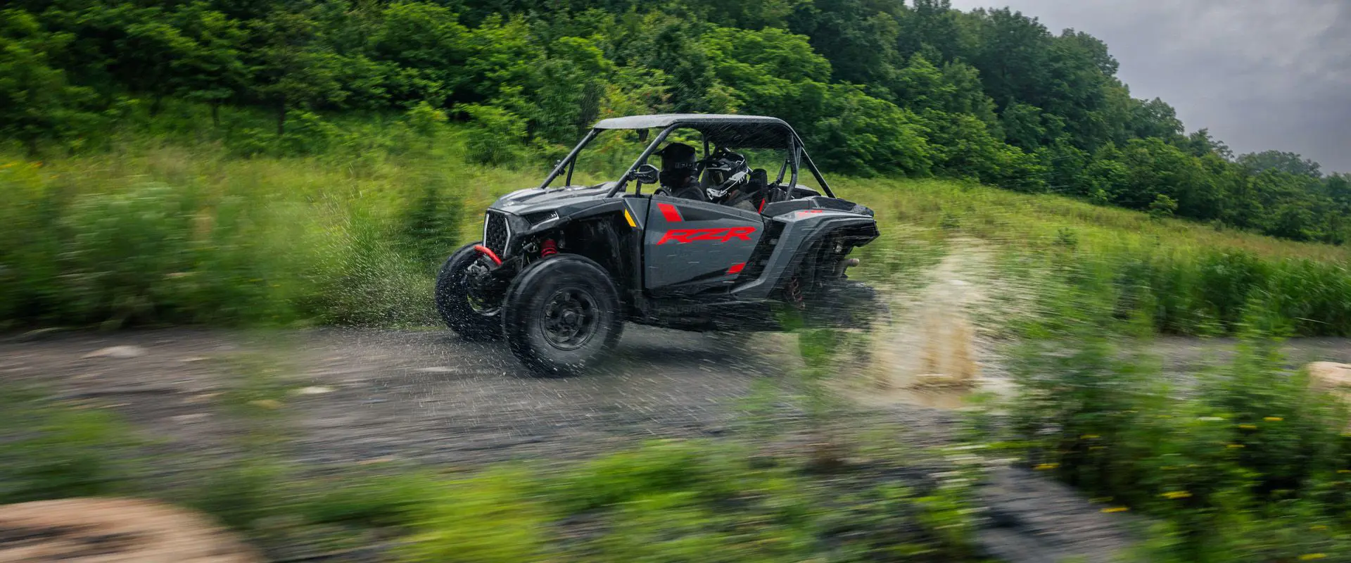 A 2026 Polaris RZR XP Ultimate SxS in the Stealth Gray colorway speeding down a trail.