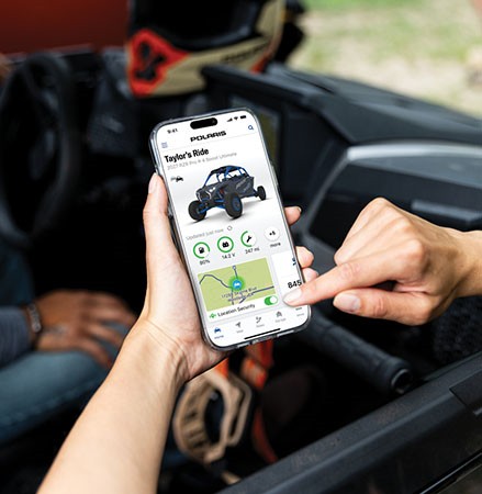 A person using RIDE COMMAND+ on their smartphone to monitor their vehicle.