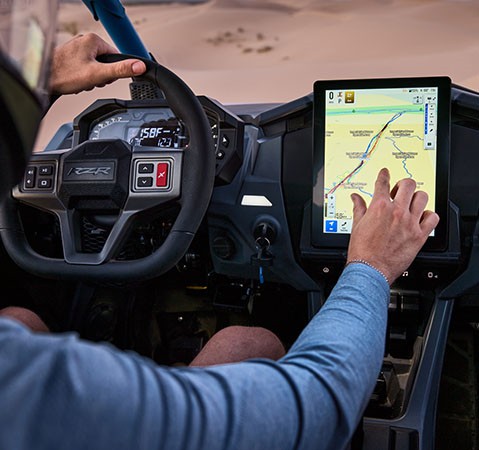 Interior of a Polaris RZR showing the steering wheel and a large, vertically oriented Polaris RIDE COMMAND display with a trail map.