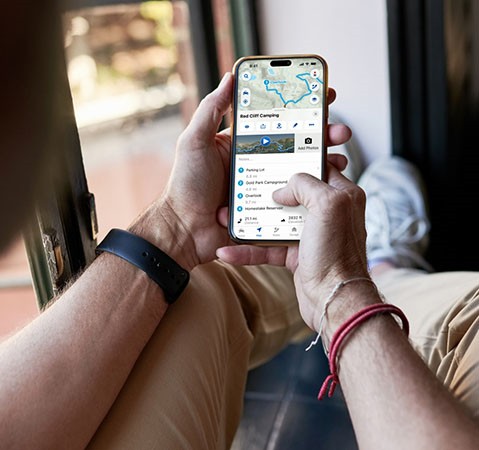 A person using the RIDE COMMAND app on their smartphone to plan a future ride.