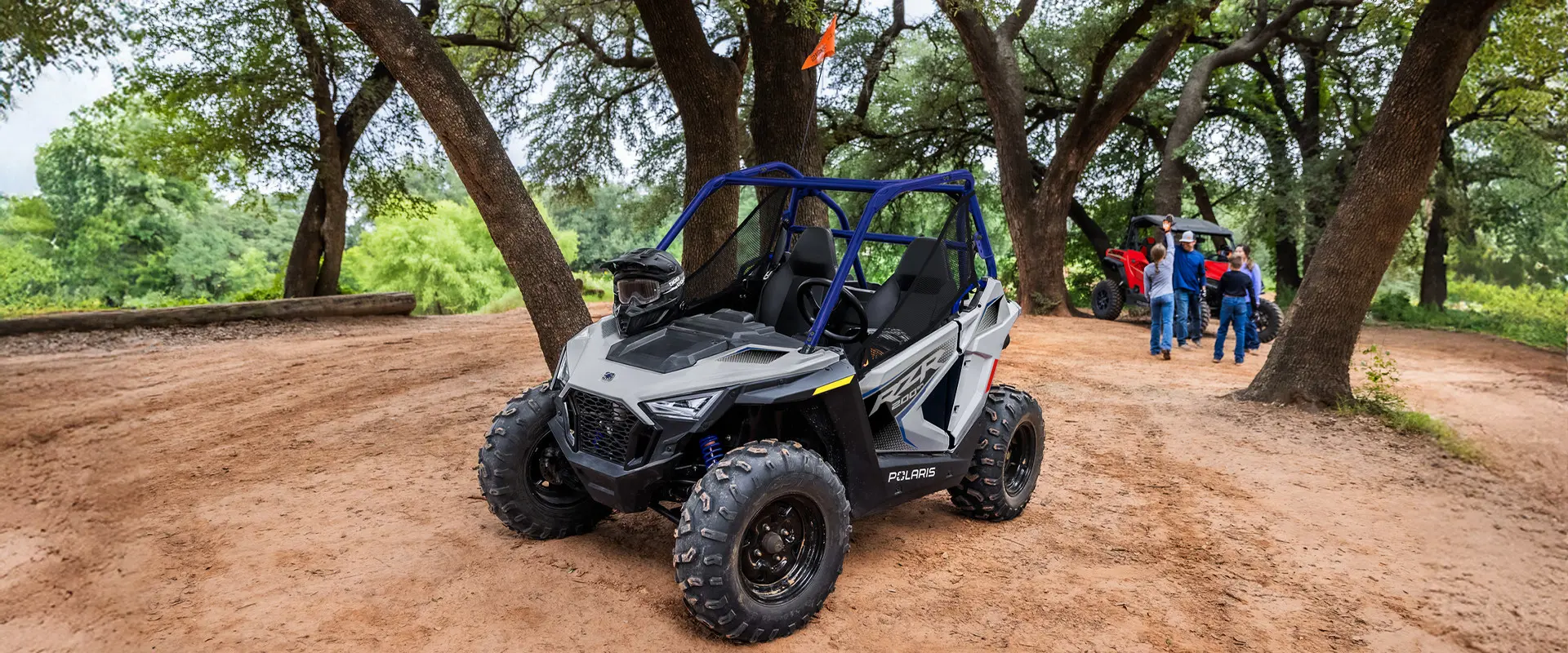 A 2027 Polaris RZR 200 EFI youth side-by-side in the Storm Gray colorway parked with a helmet on the hood.