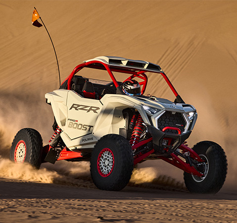 A rider in a 2027 Polaris RZR Pro R Boost side-by-side staying cool due to the rear-mounted radiator.
