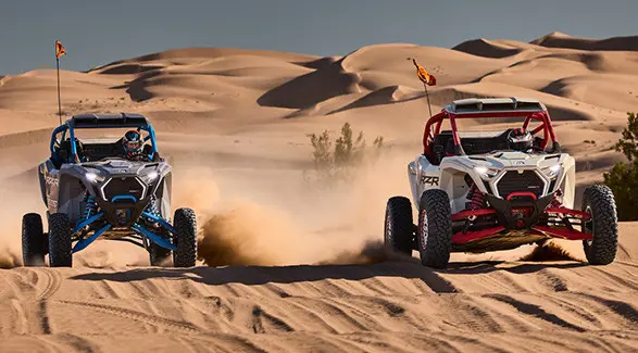 Two 2027 Polaris RZR Pro R Boost Ultimate side-by-sides driving next to each other in the desert.