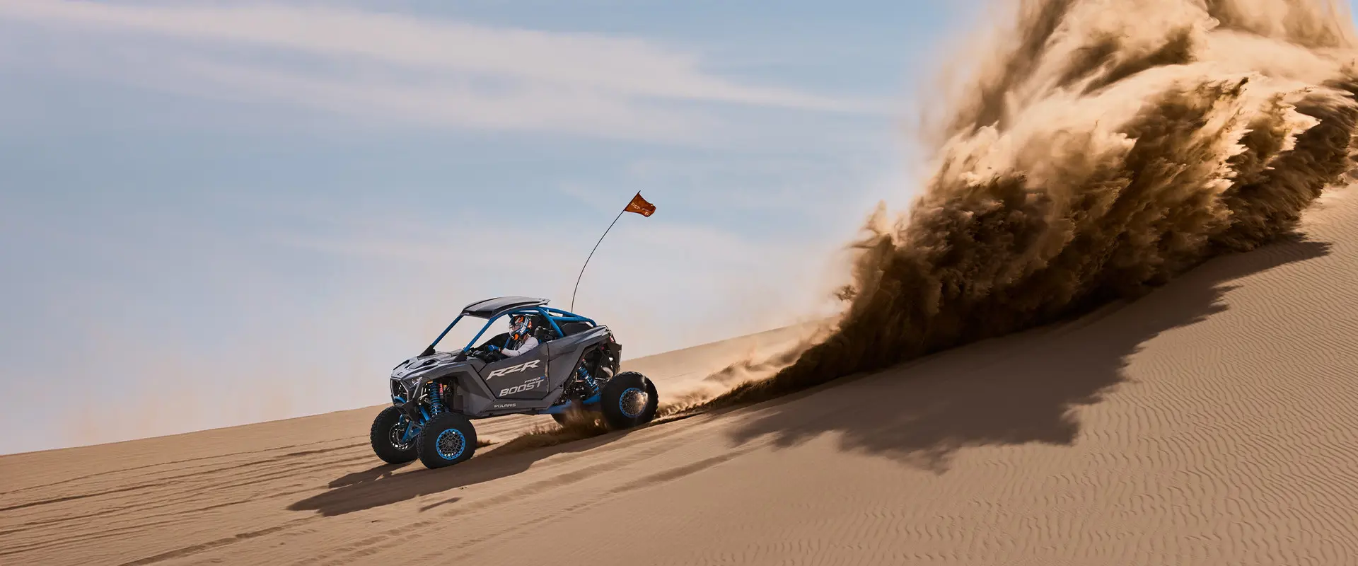 A 2027 Polaris RZR Pro R Boost Ultimate side-by-side kicking up sand in the desert.