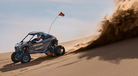 A 2027 Polaris RZR Pro R Boost Ultimate side-by-side kicking up sand in the desert.