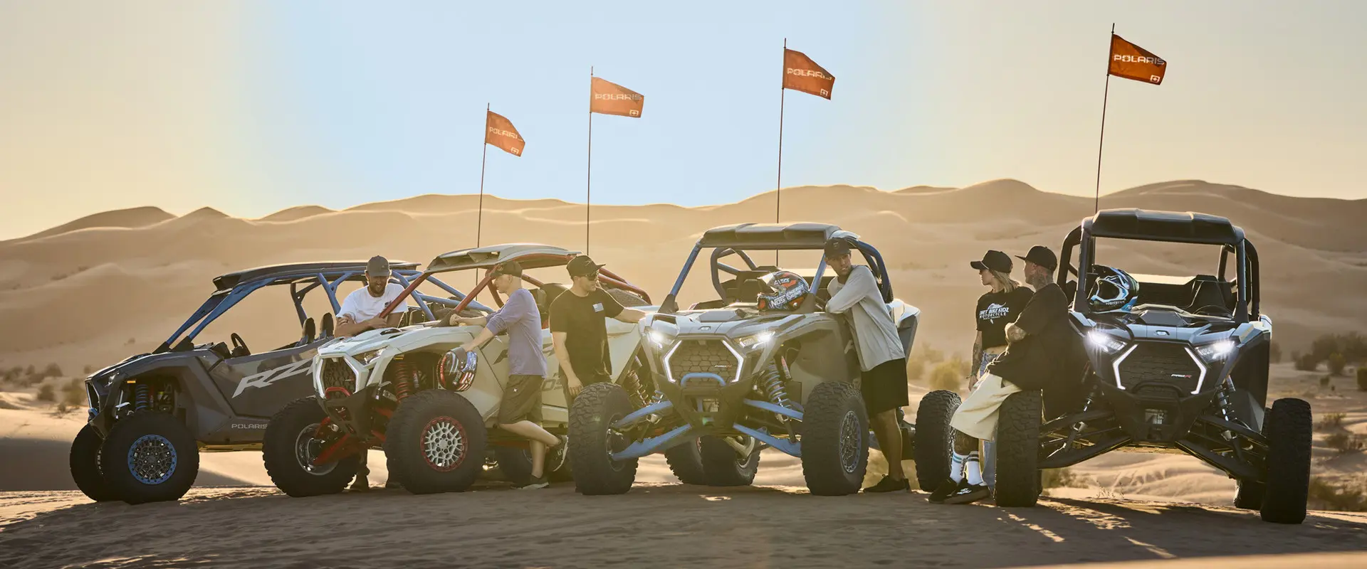6 people standing around four 2027 Polaris RZR Pro R Boost side-by-sides in the desert.