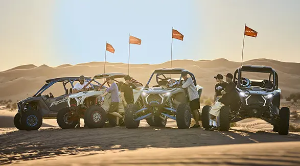 6 people standing around four 2027 Polaris RZR Pro R Boost side-by-sides in the desert.