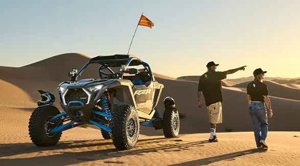 2 people pointing toward the horizon near their 2027 Polaris RZR Pro R Boost Ultimate side-by-side.