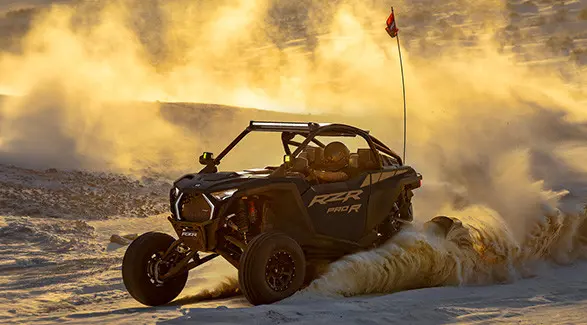 A 2027 Polaris RZR Pro R side-by-side throwing sand in the desert.