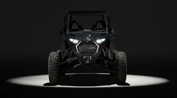 Front view of a 2027 Polaris RZR Pro R side-by-side entrenched in light in a dark room.