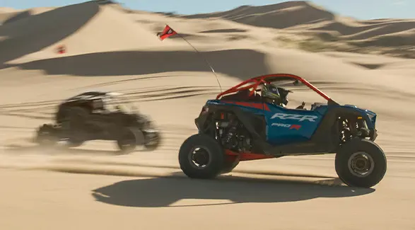 Side profile of two 2027 Polaris RZR Pro R side-by-side cruising through the desert.