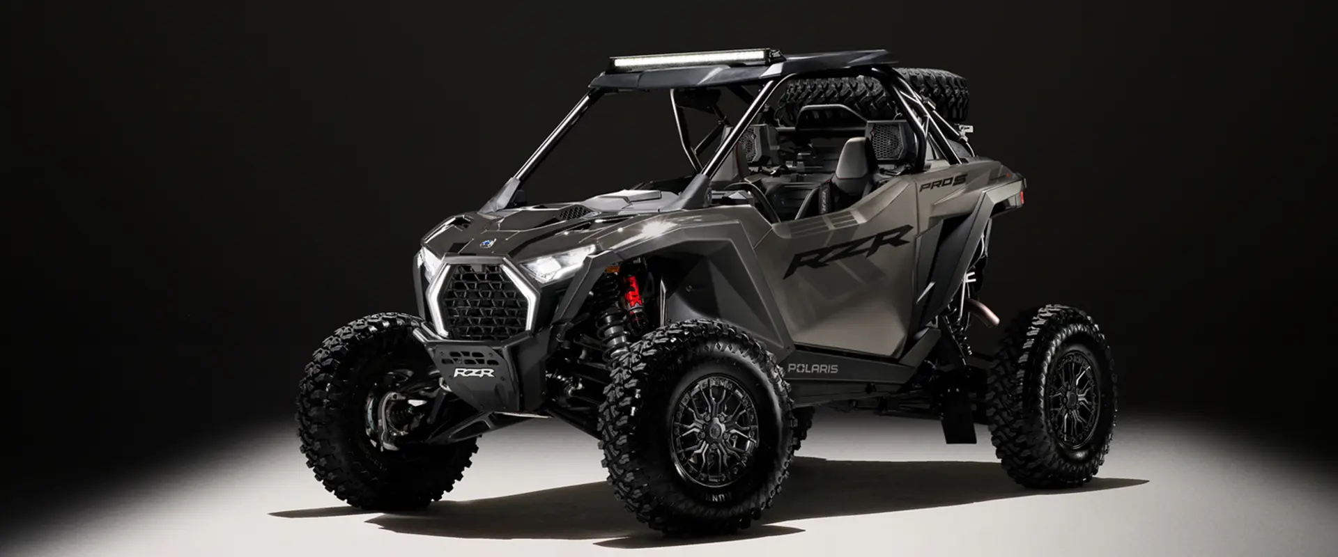 A 2027 Polaris RZR Pro S side-by-side entrenched in light in a dark room.