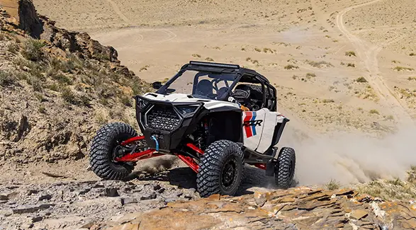 A rider in a 2027 Polaris RZR Pro S Ultimate side-by-side climbing up a rocky hill with ease.