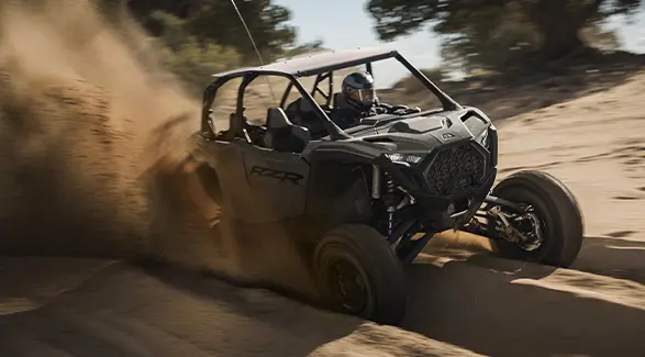 A rider in a 2027 Polaris RZR Pro S 4 side-by-side cruising down a sandy trail.