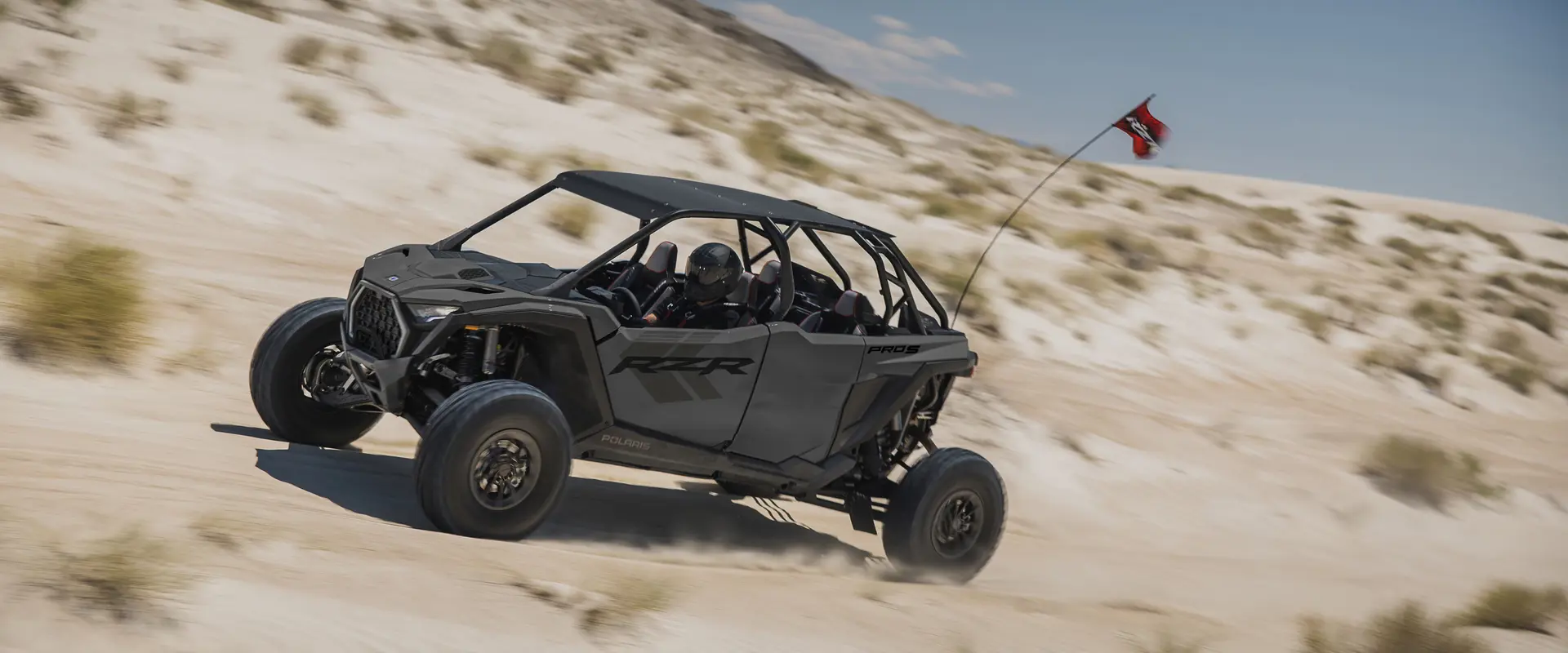 Side profile of a 2027 Polaris RZR Pro S 4 side-by-side cruising through the dunes.