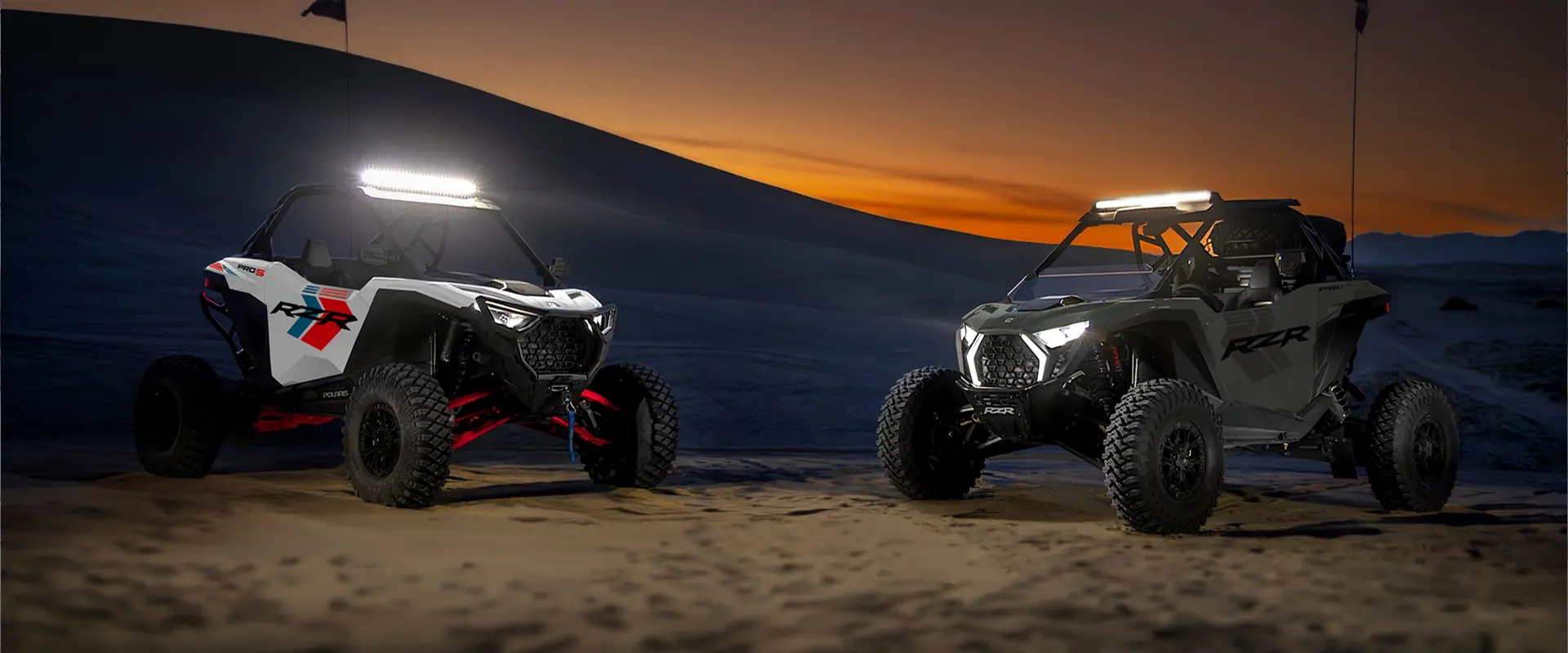 Two 2027 Polaris RZR Pro S side-by-sides with illuminated lights at sunset.