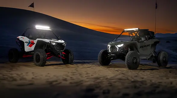 Two 2027 Polaris RZR Pro S side-by-sides with illuminated lights at sunset.