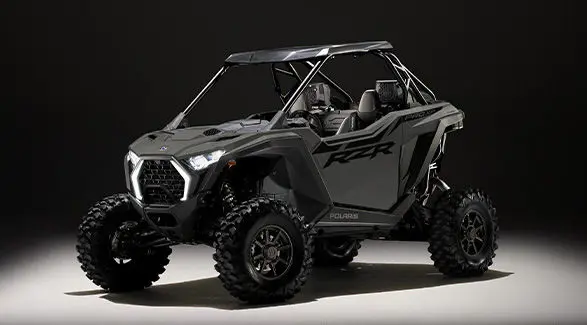 Side profile of a 2027 Polaris RZR Pro XP side-by-side entrenched in light in a dark room.