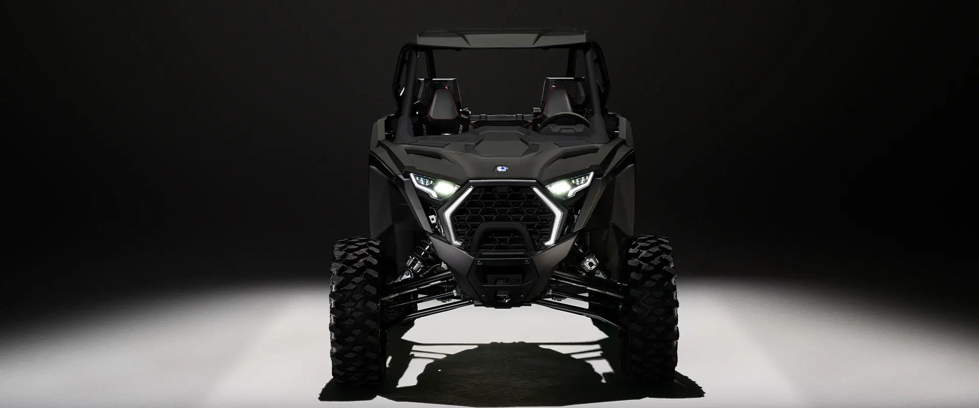 Front end view of a 2027 Polaris RZR Pro XP side-by-side entrenched in light in a dark room.