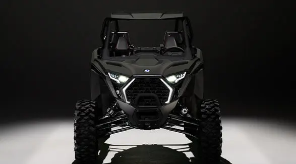 Front end view of a 2027 Polaris RZR Pro XP side-by-side entrenched in light in a dark room.