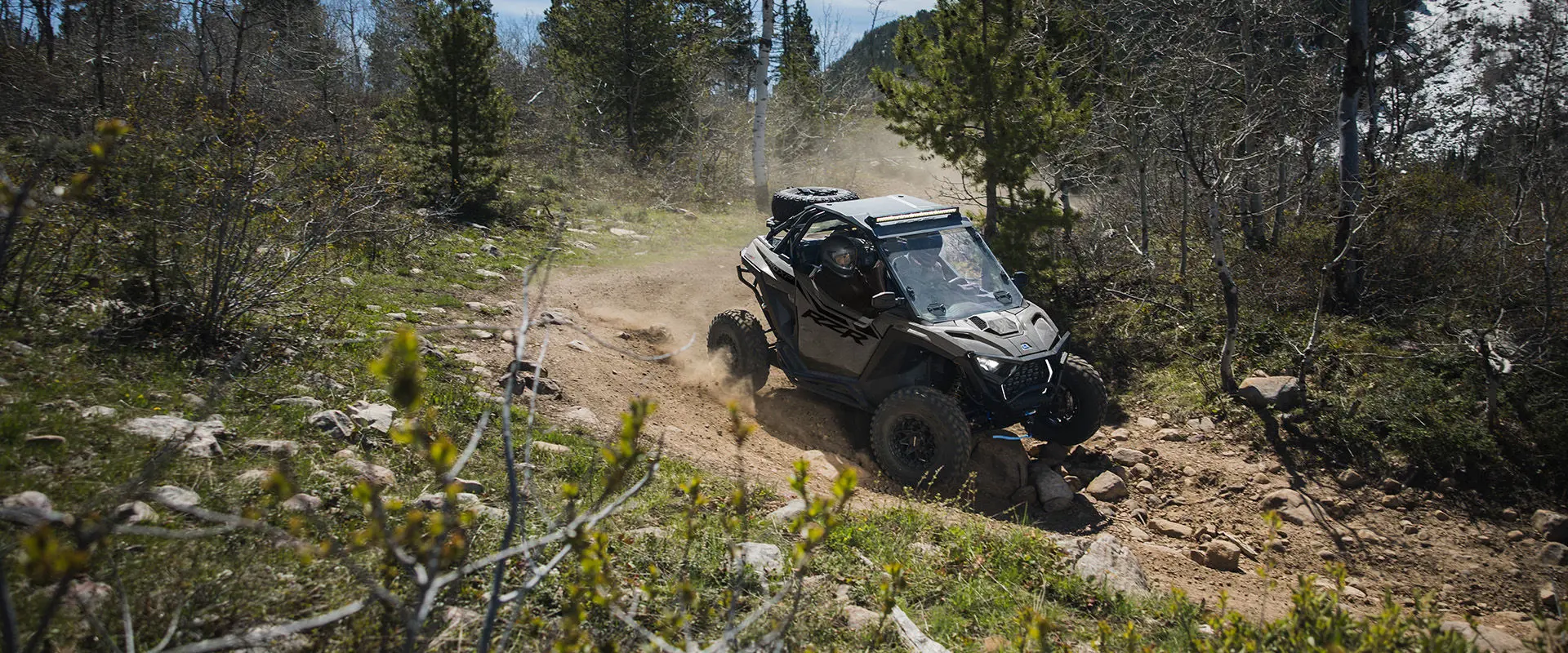 2 riders in a 2027 Polaris RZR Pro XP side-by-side driving on a rocky trail.