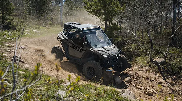 2 riders in a 2027 Polaris RZR Pro XP side-by-side driving on a rocky trail.