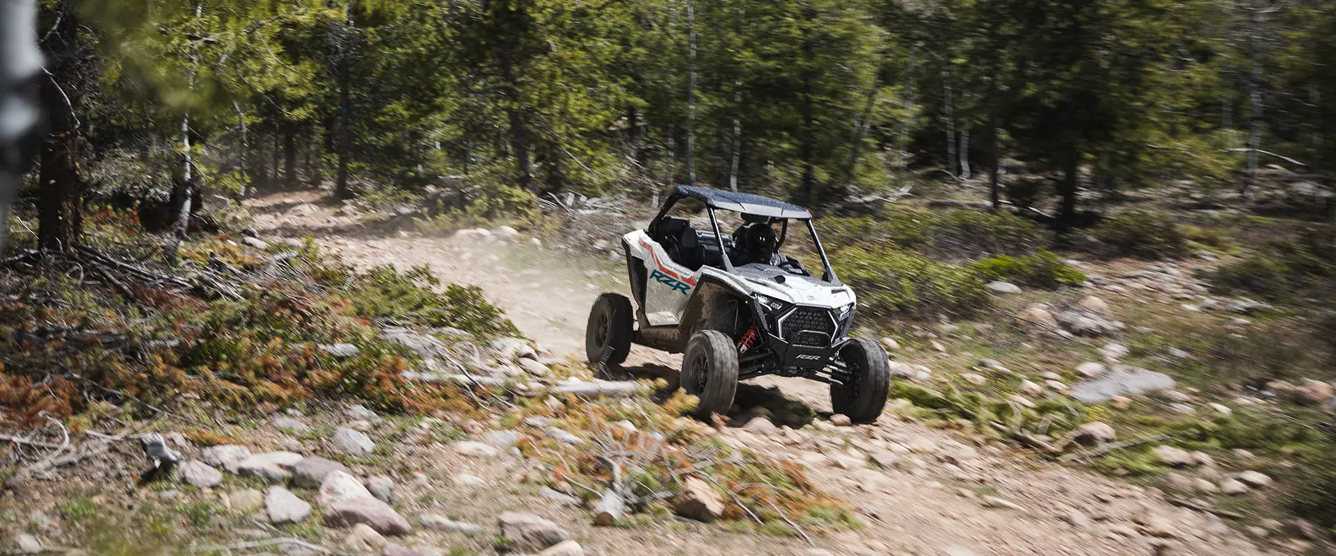 A rider in a 2027 Polaris RZR Pro XP side-by-side cruising down a rough trail.