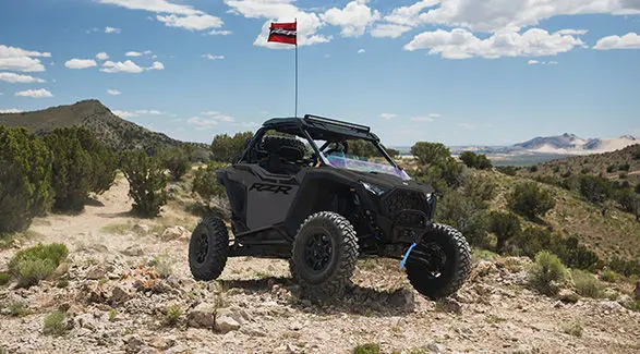 A 2027 Polaris RZR Pro XP side-by-side with it's flag up parked on a sunny day with blue skies.