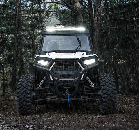 Front end view of a 2027 Polaris RZR Trail S side-by-side with illuminated headlights and lightbar.