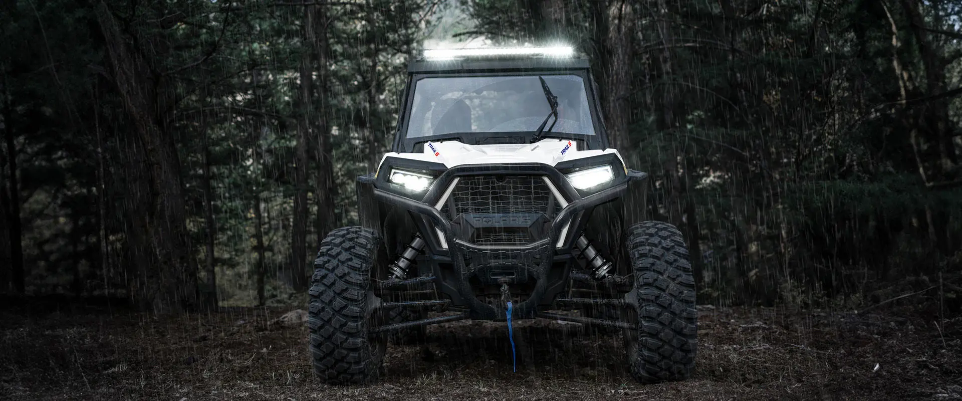 Front end view of a 2027 Polaris RZR Trail S side-by-side in the rain.