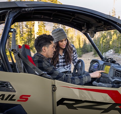 A man pointing to the RIDE COMMAND touch screen in his 2027 Polaris RZR Trail SxS.