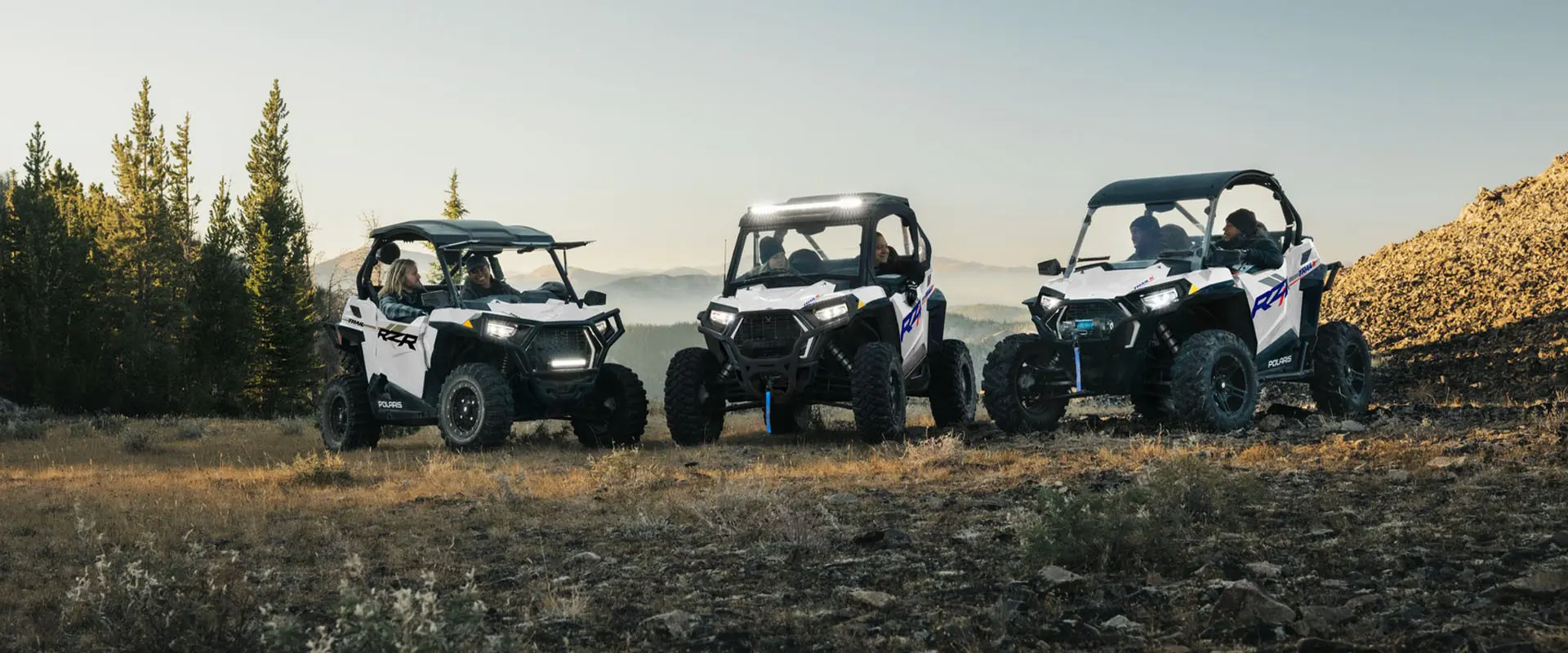 Three 2027 Polaris RZR Trail side-by-sides parked on a hillside.