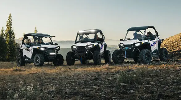 Three 2027 Polaris RZR Trail side-by-sides parked on a hillside.