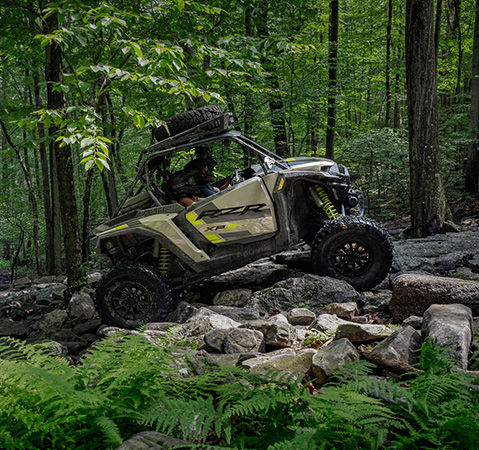 Side profile of a 2027 Polaris RZR XP S side-by-side crawling over rocky terrain.