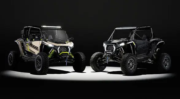 A 2027 Polaris RZR XP S 4 and a 2027 Polaris RZR XP S side-by-side entrenched in light in a dark room.