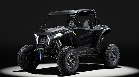 Front angle of a 2027 Polaris RZR XP S side-by-side entrenched in light in a dark room.