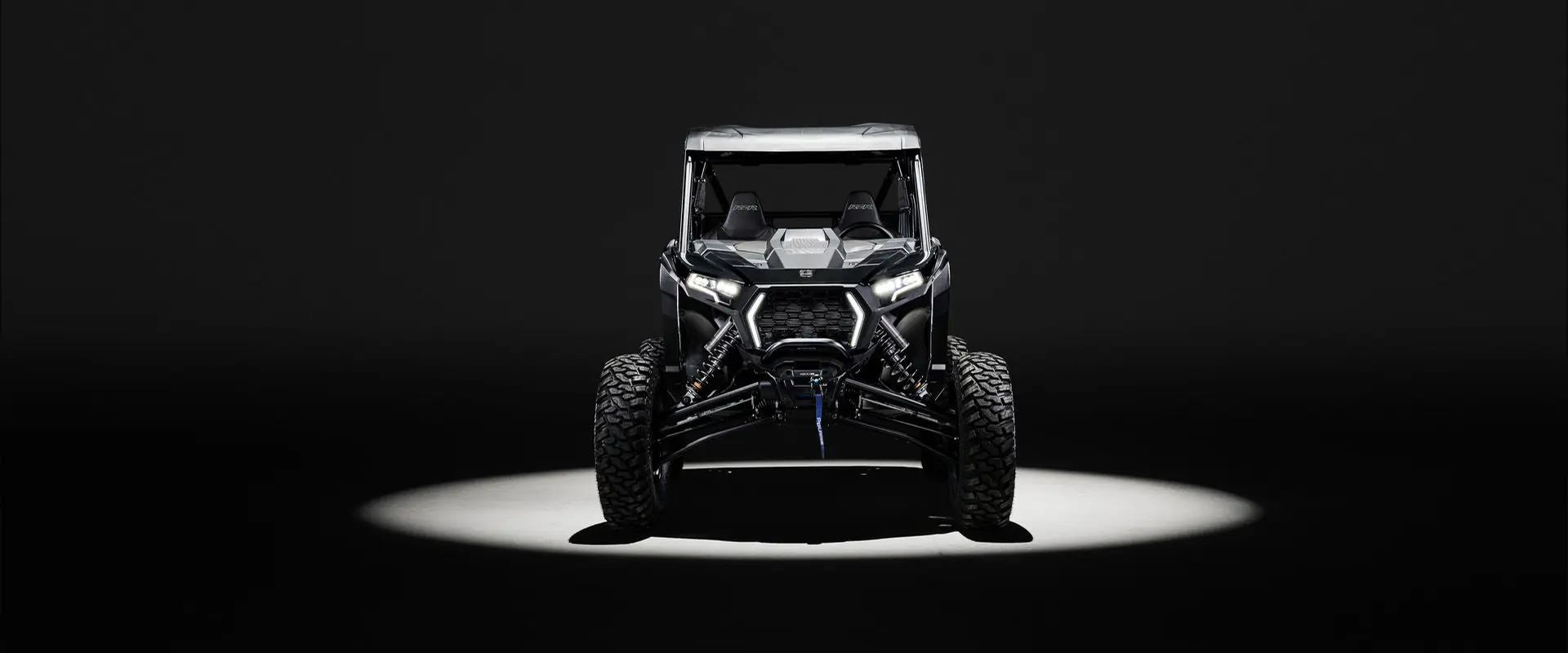 Front end of a 2027 Polaris RZR XP S side-by-side entrenched in light in a dark room.