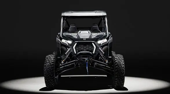 Front end of a 2027 Polaris RZR XP S side-by-side entrenched in light in a dark room.