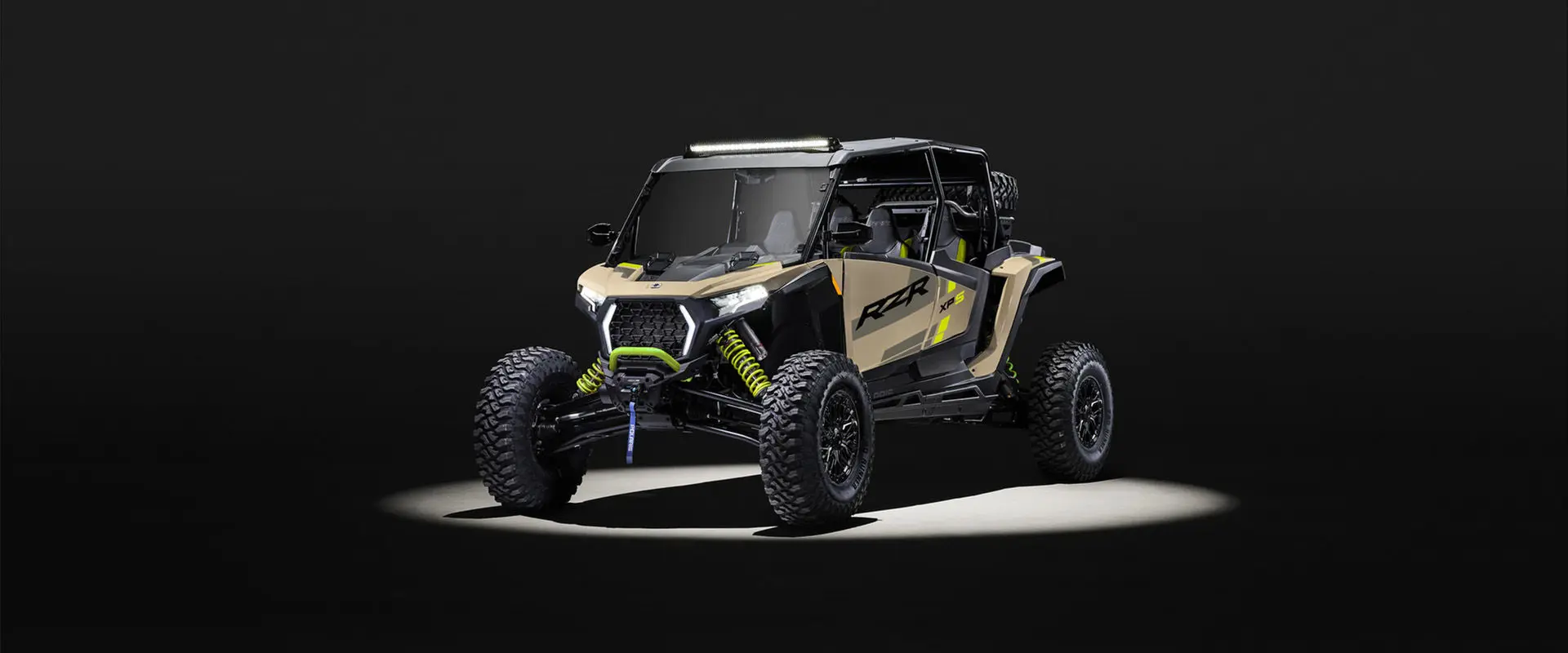 Front angle of a 2027 Polaris RZR XP S 4 side-by-side entrenched in light in a dark room.