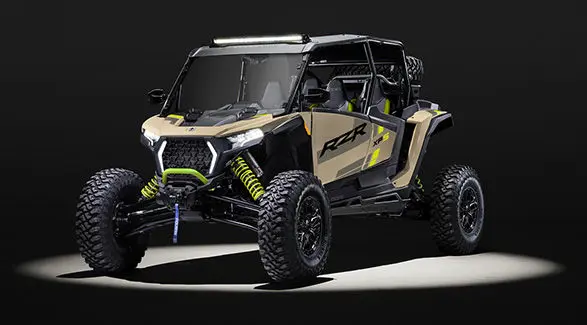 Front angle of a 2027 Polaris RZR XP S 4 side-by-side entrenched in light in a dark room.