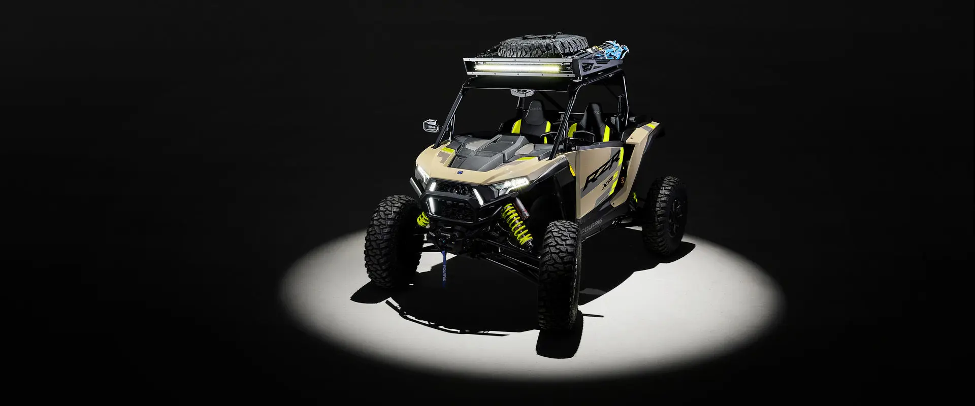 Aerial view of a 2027 Polaris RZR XP S side-by-side loaded up with accessories entrenched in light in a dark room.