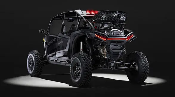 Rear view of an Onyx Black 2027 Polaris RZR XP S 4 side-by-side entrenched in light in a dark room.