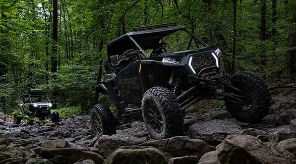2 riders in a 2027 Polaris RZR XP S side-by-side crawling over rocky terrain.